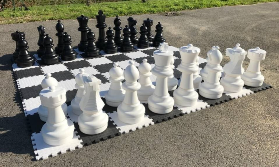 Échiquier géant en plein air avec ses pièces blanches et noires.